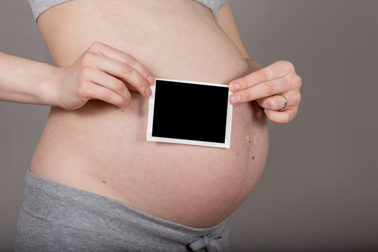 pregnant belly with ultrasound image on neutral grey background