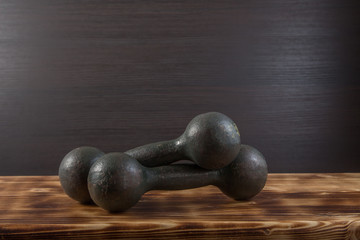 Old dumbbells on wood surface. Dark background.