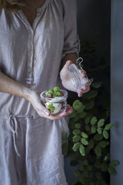 A woman holding a jar of strawberry salad with mozzarella cheese
