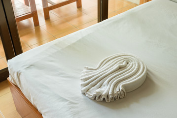 Fototapeta na wymiar White towel on bed decoration in bedroom interior.