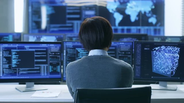 In the System Control Room Technical Operator Works at His Workstation with Multiple Displays Showing Graphics. IT Technician Works on Artificial Intelligence, Big Data Mining, Neural Network Project.