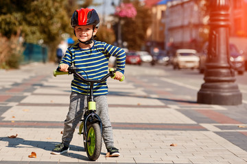 Naklejka premium Happy boy ride a bicycle in city park