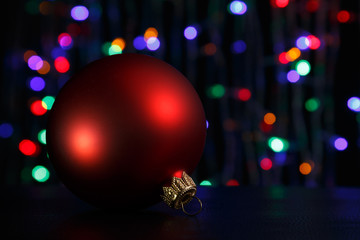 Obraz premium Red christmas ball on dark. Out of focus christmas lights background.