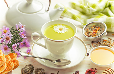 Green tea in a cup on a background of dry leaves of floral tea in a composition with accessories on a white background