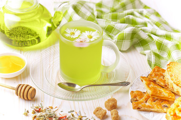 Green tea in a cup on a background of dry leaves of floral tea in a composition with accessories on a white background