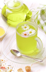 Green tea in a cup on a background of dry leaves of floral tea in a composition with accessories on a white background