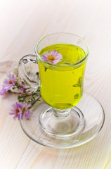 Green tea in a cup on a background of dry leaves of floral tea in a composition with accessories on a white background