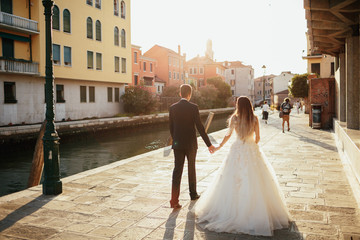 Bride and groom walk along the street somewhere in Venice