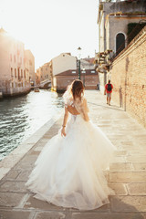 Bride runs along the canal somewhere in Venice