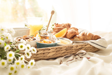 Wicker tray with continental breakfast on white bed sheets - obrazy, fototapety, plakaty