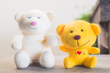white and yellow teddy bear sitting on wood floor with blur background and vintage tone