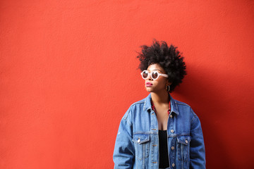 Fashionable retro style girl standing in front of a red wall