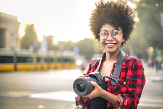 Cheerful girl walking around the city with a camera