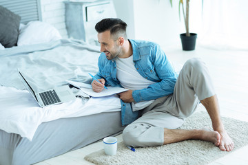 Positive male student studying at home