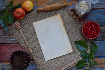 Composition of notepad, apples, cranberries, rolling pin, molds for muffins, oatmeal. Preparation for kneading dough, baking cookie or muffin. Space for text or recipe.