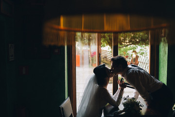 Pretty wedding couple sits at wooden table in the cafe