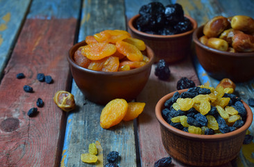Composition from different varieties of dried fruits on wooden background - dates, apricots, prunes, raisins. Healthy food