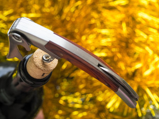 The corkscrew opens a bottle of wine on a festive bright background.
