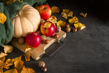 Naklejka na ściany i meble Autumn meal apples, nuts, pumpkin and yellow leaves. Dark backgr