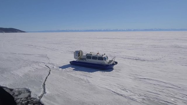 Khivus boat hovercraft tourist entertainment. Baikal lake edge Russia Siberia Frozen. Floats next to Angara river ice Landscape space High rocks. Snow winter sunny day. Best Aerial From above