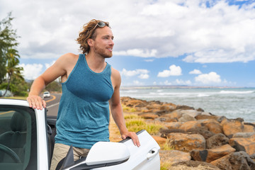 Driving man on road trip convertible car travel looking at nature scenery from cabriolet sports automobile on summer vacation. Happy young male traveler in tropical destination.