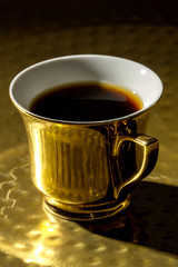 A cup of coffee on a golden tray