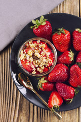 Strawberries and strawberry dessert with muesli on a grey plate