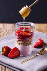 Yogurt with musli and strawberries poured with honey