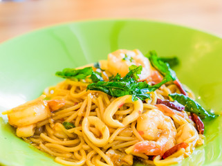 Spicy Spaghetti Seafood in a green plate on wooden background