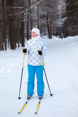 Woman in ski-wear with ski poles standing in wintry forest