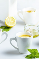 Cups of mint tea with lemon and honey on a white table