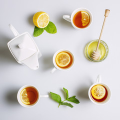 Cups of black tea with lemon and ceramic kettle, view from top