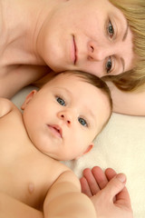 Portrait of the young woman with the baby on a light background