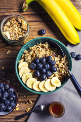 Healthy breakfast - muesli with banana and blueberries on a wooden table