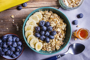 Delicious muesli with blueberries, honey and banana on a wooden table