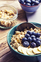 Granola with fresh blueberries, banana, honey and seeds on a wooden table