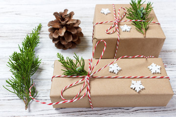Christmas composition. Christmas gift, knitted blanket, pine cones, fir branches on wooden white background. Flat lay, top view