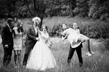 Fototapeta na wymiar Crazy and happy newlyweds having fun with bridesmaids and groomsmen in the park.