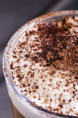 Coffee with whipped cream sprinkled with dark cocoa, closeup