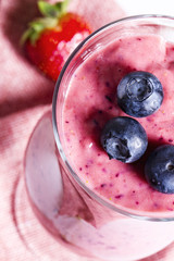Healthy strawberry smoothie with blueberries on a pink napkin