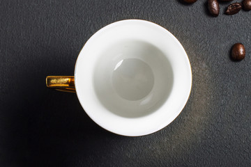 Empty golden ceramic cup on black, top view