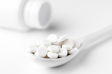 Pills on the spoon and scattered on the white surface