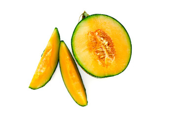 Ripe yellow melon with seeds cut in half with slices nearby. Isolate on white background.