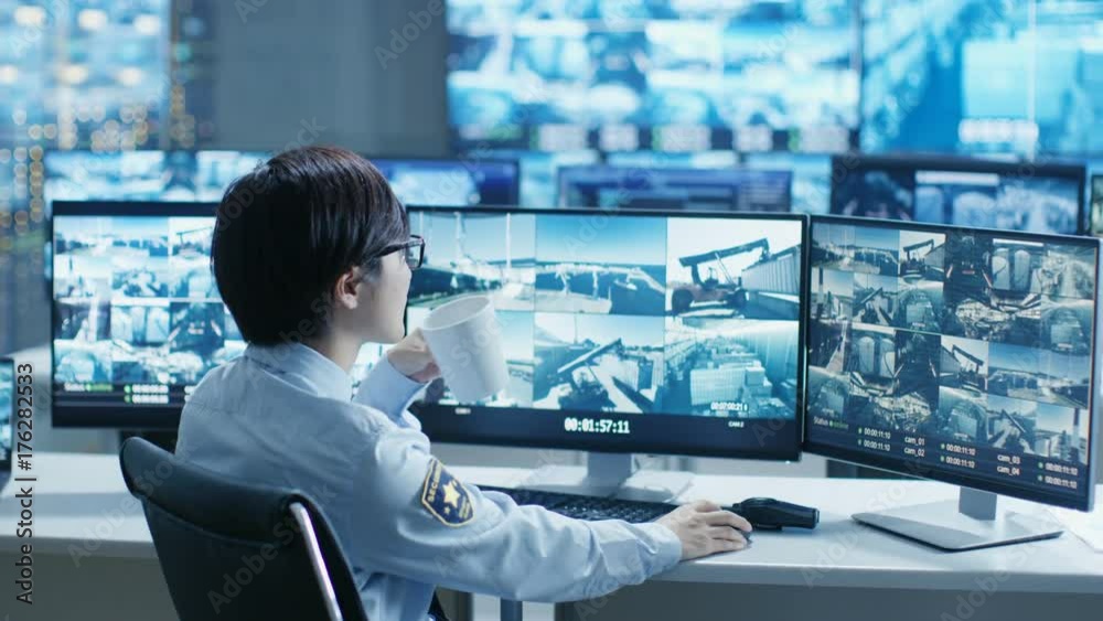 Poster in the security control room officer monitors multiple screens for suspicious activities, he drinks 