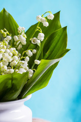 A bouquet of lilies of the valley in a white ceramic vase