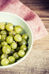 Gooseberries in a mint bowl on wooden background