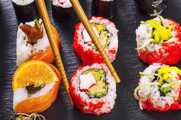 Caviar sushi rolls and chopsticks on a stone background