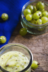 Fresh gooseberry smoothie and gooseberries in a glass on wooden table, view from top