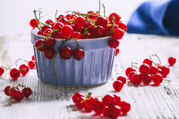 Red currant in a blue bowl on a wooden table
