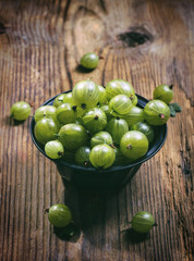 Ripe gooseberries in a metal bowl on wooden table